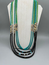 Load image into Gallery viewer, This striking and bold skull necklace is a must-have addition to any jewelry collection. Featuring five strands of glass and bone beads, this hand-beaded necklace is crafted with a combination of beautiful earth-tone colors to complement any outfit. Measurements: Necklace: Shortest strand is 29 1/2” and longest strand 35 1/2"