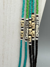 Load image into Gallery viewer, This striking and bold skull necklace is a must-have addition to any jewelry collection. Featuring five strands of glass and bone beads, this hand-beaded necklace is crafted with a combination of beautiful earth-tone colors to complement any outfit. Measurements: Necklace: Shortest strand is 29 1/2” and longest strand 35 1/2"