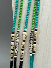 Load image into Gallery viewer, This striking and bold skull necklace is a must-have addition to any jewelry collection. Featuring five strands of glass and bone beads, this hand-beaded necklace is crafted with a combination of beautiful earth-tone colors to complement any outfit. Measurements: Necklace: Shortest strand is 29 1/2” and longest strand 35 1/2"