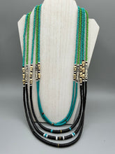 Load image into Gallery viewer, This striking and bold skull necklace is a must-have addition to any jewelry collection. Featuring five strands of glass and bone beads, this hand-beaded necklace is crafted with a combination of beautiful earth-tone colors to complement any outfit. Measurements: Necklace: Shortest strand is 29 1/2” and longest strand 35 1/2"