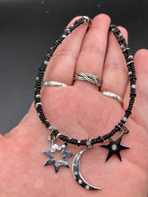 Load image into Gallery viewer, Whimsical Celestial Crescent Moon And Stars Collar Stye Adjustable Glass Beaded Necklace. Two strands are held together with double-hole black and silver beads to keep a collar shape. This necklace beautifully drapes across your neck, a fierce, bold and elegant piece of jewelry. Perfect for Goth, Witchy, and Stardust Celestial Styles.  Measurements:    Necklace is 15” in length (“collar” style), can be adjusted up to 18"