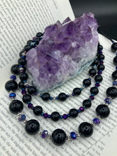 Load image into Gallery viewer, This Bohemian style necklace is composed of three strands of shimmery large black and dark purple glass beads, along with floral metal beads. The elegant drape creates a bold and fierce look that is ideal for a variety of occasions, such as cocktail chic attire and weddings. It is a perfect minimalist accessory.  Measurements:  Necklace is 16” in length - adjustable to 18"