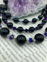 Load image into Gallery viewer, This Bohemian style necklace is composed of three strands of shimmery large black and dark purple glass beads, along with floral metal beads. The elegant drape creates a bold and fierce look that is ideal for a variety of occasions, such as cocktail chic attire and weddings. It is a perfect minimalist accessory.  Measurements:  Necklace is 16” in length - adjustable to 18"