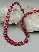 Load image into Gallery viewer, This ruby red heart-shaped glass beaded necklace features a shimmery and vivid iridescent hue, secured with a hook-eye clasp. Measurements:    Necklace is 19" in length