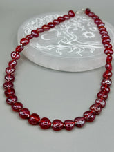 Load image into Gallery viewer, This ruby red heart-shaped glass beaded necklace features a shimmery and vivid iridescent hue, secured with a hook-eye clasp. Measurements:    Necklace is 19" in length