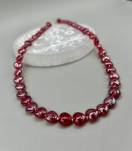 Load image into Gallery viewer, This ruby red heart-shaped glass beaded necklace features a shimmery and vivid iridescent hue, secured with a hook-eye clasp. Measurements:    Necklace is 19" in length