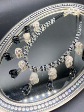 Load image into Gallery viewer, Black And White Vampire Goth Skulls Choker Style Necklace, Skully Witchy Vibe, Goth Dark Souls Jewelry, Day Of The Dead, Dia De Los Muertos, Howlite Skull Beads Black And Silver Glass BeadsThis statement necklace radiates a dark, shimmering aesthetic with two strands of glass beads connected through double-hole silver and black beads to create a collar shape. These dangling skulls beads are acompanied by black teardrop glass beads enable the piece to flow elegantly and express a bold, fierce look.