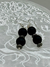 Load image into Gallery viewer, These flat matte black round glass bead earrings with silver plated floral beads offer a versatile look perfect for cocktail chic attire, a wedding necklace, and minimalist style. Measurements: 1 1/4” in length