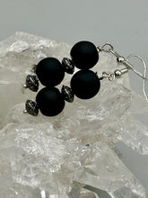 Load image into Gallery viewer, These flat matte black round glass bead earrings with silver plated floral beads offer a versatile look perfect for cocktail chic attire, a wedding necklace, and minimalist style. Measurements: 1 1/4” in length
