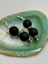 Load image into Gallery viewer, These flat matte black round glass bead earrings with silver plated floral beads offer a versatile look perfect for cocktail chic attire, a wedding necklace, and minimalist style. Measurements: 1 1/4” in length