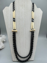Load image into Gallery viewer, This two-strand necklace features a selection of natural black obsidian stone, hematite, bone, and glass beads. This neutral-hued accessory enhances any ensemble. Measurements: Necklace is 29” in length, can be adjusted up to 30" in length