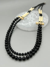 Load image into Gallery viewer, This two-strand necklace features a selection of natural black obsidian stone, hematite, bone, and glass beads. This neutral-hued accessory enhances any ensemble. Measurements: Necklace is 29” in length, can be adjusted up to 30" in length