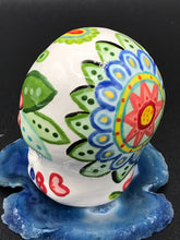 Load image into Gallery viewer, Inspired by nature, this ceramic skull statuette is full of vibrant color and intricate details that I hand painted. The primary color is white with multi-color floral motifs that are painted across the skull, along with hearts and leaves and lively colorful accents around the entire skull.