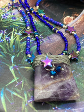 Load image into Gallery viewer, This elegant amethyst trapezoid pendant is artfully wirewrapped with a hematite star bead, making this a unique piece perfect for any occasion. Its two strands of colorful glass beads in a mix of cool blues, purples, and silver create an enchanting, starry night look sure to make a statement. Necklace is 16” in length and can be adjusted to 18"