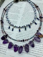 Load image into Gallery viewer, The Genuine Amethyst Natural Gemstone Adjustable Chocker Style Glass Beaded Necklace features vibrant violet and white tones. Its unique draped beading creates a beautiful style with a series of short strands of glass beads for movement and a longer strand with a multitude of amethyst nugget beads. The collar necklace hangs gracefully along the neck and chest, making it a dream come true for violet lovers.  Measurements:  Necklace is 15” in length adjustable to 18" in length