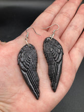 Load image into Gallery viewer, Shimmery black angel wings earrings made of polymer clay. These earrings are designed to face forward when worn instead of the front wings showing on the side.