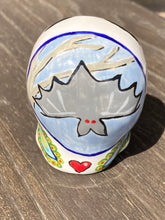 Load image into Gallery viewer, This Bat Lovers Ceramic Skull Art is a unique addition to any dark gothic collection. Featuring a mini batty with bright red eyes and outlined in royal blue, accented with white lines to highlight its small bones and an additional bat with vibrant red eyes on the opposite side. Enjoy the playful contrast of warm tones and a darker theme in this eye-catching figurine. Measurements: H 2 3/4” x W 2” x D 2”