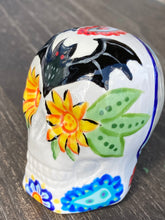 Load image into Gallery viewer, This Ceramic Skull Art With Bat Silhouettes And Flowers is a beautiful mini goth witchy altar skull, with detailed hand painted features. Inspired by the vibrant blooms of the Dawn Redwood, it captures the beauty of the changing of seasons. Perfect for adding a touch of whimsical enchantment to any home. Measurements: H 2 3/4” x W 2” x D 2”