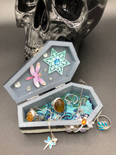 Load image into Gallery viewer, Handmade Vintage Inspired Gothic Victorian Coffin Jewelry Box. Black Wood Coffin Ring Box, Seafoam Blue Star Shape Veneer Floral Embellishment. Dark and whimsical theme keepsake box with dragonfly and shimmer gems. Starry Night Jewelry Box. Interior lined mandala pattern fabric. Holds several rings or jewelry pieces. Dark, Beautiful, Unique Gift for the BOLD. Makes a great keepsake box! Or you could also just let your cat admire it before he knocks it off the table, too.