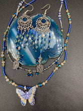 Load image into Gallery viewer, These intricate moroccan blue Inspired large chandelier earrings boast five strands of blue and iridescent glass beads of various hues, including silver and gold. Additionally, two small dark blue glass beads with a silver leaf add a touch of dimension and motion. The perfect addition to any Fairy Princess or whimsical aesthetic.  Measurements: 4” in length