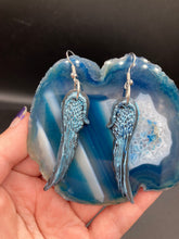 Load image into Gallery viewer, Sparkling light blue angel wings earrings made of polymer clay. These earrings are designed to face forward when worn instead of the front wings showing on the side.