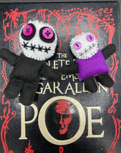 Load image into Gallery viewer, Creepy black and purple Voodoo Doll stands tall at 3 3/8" in height. He’s all black like a shadow but has a round white head. Bright purple buttons for eyes are perfect to see you better with. Mini socially awkward black and purple Voodoo Doll stands at 2 3/4" in height. He has a bright purple torso with black limbs and a large white head and matching purple biddy eyes.
