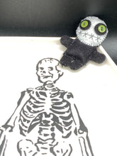 Load image into Gallery viewer, Black and white Voodoo Doll stands at 3" in height. He has an all black body with a white round head. Bulging lime green button eyes and sowed shut mouth to give him a little creepy face of course.