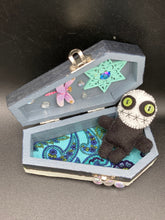 Load image into Gallery viewer, Black and white Voodoo Doll stands at 3" in height. He has an all black body with a white round head. Bulging lime green button eyes and sowed shut mouth to give him a little creepy face of course.