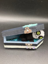 Load image into Gallery viewer, Black and white Voodoo Doll stands at 3" in height. He has an all black body with a white round head. Bulging lime green button eyes and sowed shut mouth to give him a little creepy face of course.