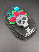 Load image into Gallery viewer, Showcasing a dark theme Frida Kahlo inspired calavera with a dark wood frame, this Day of the Dead wall decor piece is perfect for adding a traditional Mexican folk art touch to any home. Featuring an intricately detailed clay calavera in the style of Frida Kahlo, this Day of the Dead wall art decor is sure to be the centerpiece of any home décor. The calavera is wearing Frida's iconic crown of flowers, ensuring it will bring both a unique and inspiring look to any wall.