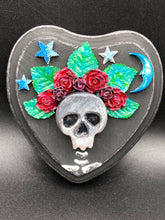 Load image into Gallery viewer, Showcasing a dark theme Frida Kahlo inspired calavera with a dark wood frame, this Day of the Dead wall decor piece is perfect for adding a traditional Mexican folk art touch to any home. Featuring an intricately detailed clay calavera in the style of Frida Kahlo, this Day of the Dead wall art decor is sure to be the centerpiece of any home décor. The calavera is wearing Frida's iconic crown of flowers, ensuring it will bring both a unique and inspiring look to any wall.