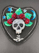 Load image into Gallery viewer, Showcasing a dark theme Frida Kahlo inspired calavera with a dark wood frame, this Day of the Dead wall decor piece is perfect for adding a traditional Mexican folk art touch to any home. Featuring an intricately detailed clay calavera in the style of Frida Kahlo, this Day of the Dead wall art decor is sure to be the centerpiece of any home décor. The calavera is wearing Frida's iconic crown of flowers, ensuring it will bring both a unique and inspiring look to any wall.