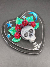 Load image into Gallery viewer, Showcasing a dark theme Frida Kahlo inspired calavera with a dark wood frame, this Day of the Dead wall decor piece is perfect for adding a traditional Mexican folk art touch to any home. Featuring an intricately detailed clay calavera in the style of Frida Kahlo, this Day of the Dead wall art decor is sure to be the centerpiece of any home décor. The calavera is wearing Frida's iconic crown of flowers, ensuring it will bring both a unique and inspiring look to any wall.