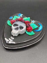 Load image into Gallery viewer, Showcasing a dark theme Frida Kahlo inspired calavera with a dark wood frame, this Day of the Dead wall decor piece is perfect for adding a traditional Mexican folk art touch to any home. Featuring an intricately detailed clay calavera in the style of Frida Kahlo, this Day of the Dead wall art decor is sure to be the centerpiece of any home décor. The calavera is wearing Frida's iconic crown of flowers, ensuring it will bring both a unique and inspiring look to any wall.