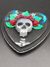 Load image into Gallery viewer, Showcasing a dark theme Frida Kahlo inspired calavera with a dark wood frame, this Day of the Dead wall decor piece is perfect for adding a traditional Mexican folk art touch to any home. Featuring an intricately detailed clay calavera in the style of Frida Kahlo, this Day of the Dead wall art decor is sure to be the centerpiece of any home décor. The calavera is wearing Frida's iconic crown of flowers, ensuring it will bring both a unique and inspiring look to any wall.