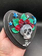 Load image into Gallery viewer, Showcasing a dark theme Frida Kahlo inspired calavera with a dark wood frame, this Day of the Dead wall decor piece is perfect for adding a traditional Mexican folk art touch to any home. Featuring an intricately detailed clay calavera in the style of Frida Kahlo, this Day of the Dead wall art decor is sure to be the centerpiece of any home décor. The calavera is wearing Frida's iconic crown of flowers, ensuring it will bring both a unique and inspiring look to any wall.