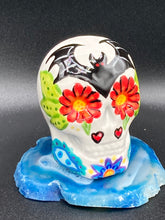 Load image into Gallery viewer, This mini ceramic sugar skull is an intricate piece of art, inspired by nature and drenched in vibrant colors and details. Featuring a white base and multi-colored floral motifs, notable features include hearts and leaves as well as lively accents that encircle the skull. A beautiful Dia De Los Muertos or Day of the Dead-themed decoration. Measurements: H 2 3/4” x W 2” x D 2”