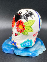 Load image into Gallery viewer, This mini ceramic sugar skull is an intricate piece of art, inspired by nature and drenched in vibrant colors and details. Featuring a white base and multi-colored floral motifs, notable features include hearts and leaves as well as lively accents that encircle the skull. A beautiful Dia De Los Muertos or Day of the Dead-themed decoration. Measurements: H 2 3/4” x W 2” x D 2”