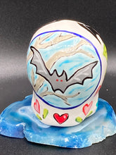 Load image into Gallery viewer, This mini ceramic sugar skull is an intricate piece of art, inspired by nature and drenched in vibrant colors and details. Featuring a white base and multi-colored floral motifs, notable features include hearts and leaves as well as lively accents that encircle the skull. A beautiful Dia De Los Muertos or Day of the Dead-themed decoration. Measurements: H 2 3/4” x W 2” x D 2”