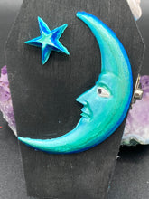 Load image into Gallery viewer, This sleek black box has an eye-catching turquoise crescent at its center, accompanied by a bright blue ribbon and a dainty white moon. Inside, the interior is decorated with a vivid royal blue and detailed with a small crescent moon and black-and-silver cross. Coffin Dimensions: Length: 4 1/2 Inches; Width: 2 1/2 inches; Height: 1 5/8 Inches