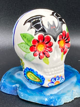 Load image into Gallery viewer, Inspired by nature, this ceramic skull statuette is full of vibrant color and intricate details. The primary color is white with a batty for bats theme and with multi-color floral motifs, along with hearts and leaves and lively colorful accents around the entire skull. Measurements: H 2 3/4” x W 2” x D 2”