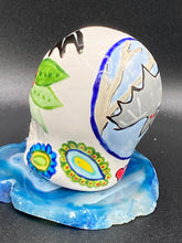 Load image into Gallery viewer, Inspired by nature, this ceramic skull statuette is full of vibrant color and intricate details. The primary color is white with a batty for bats theme and with multi-color floral motifs, along with hearts and leaves and lively colorful accents around the entire skull. Measurements: H 2 3/4” x W 2” x D 2”