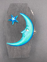 Load image into Gallery viewer, This sleek black box has an eye-catching turquoise crescent at its center, accompanied by a bright blue ribbon and a dainty white moon. Inside, the interior is decorated with a vivid royal blue and detailed with a small crescent moon and black-and-silver cross. Coffin Dimensions: Length: 4 1/2 Inches; Width: 2 1/2 inches; Height: 1 5/8 Inches