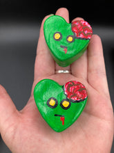 Load image into Gallery viewer, Perfect cute and spooky Halloween item to add to your fridge, locker, cubicle or toolbox. This handcrafted, bright green, heart-shaped magnet features an intricate, exposed brains-inspired zombie design. Measurements: H 1 1/2” x W 1 5/8” x D 1/2”
