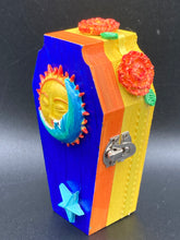 Load image into Gallery viewer, This coffin-shaped box features a bright royal blue exterior, with a bold sun and crescent adorning the center. Complemented with marigold flowers, the inside is painted in a bright red hue with turquoise and yellow cross detailing and traditional Mexican-themed fabric. Coffin Dimensions: Length: 4 1/2 Inches; Width: 2 1/2 inches; Height: 1 5/8 Inches