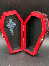 Load image into Gallery viewer, Super vibrant red coffin box has an eye-catching black and gray embellishment in the center, accompanied by a glittery black ribbon around the coffin. Inside, the interior is all black with a floral detailed black-silver cross.