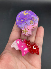 Load image into Gallery viewer, Cute and spooky magnet design to adorn your refrigerator, lockers, workstation, toolbox, or dishwasher. This hand-sculpted clay skull and bat statuette boasts stunning ombre coloration, transitioning from dark purple to light pink and light pink to dark redto recreate the breathtaking look of a starry night sky.