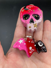 Load image into Gallery viewer, Cute and spooky magnet design to adorn your refrigerator, lockers, workstation, toolbox, or dishwasher. This intricately detailed skull statuette is inspired by the beauty of nature, with vibrant colors ranging from red to a light pink reminiscent of a summer sky at dusk. A black moon and gold stars were added to provide a unified aesthetic.