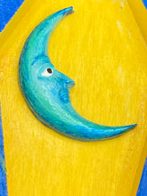 Load image into Gallery viewer, This coffin-shaped box features a bright royal blue exterior, with a bold sun and crescent adorning the center. Complemented with a shimmery pastel-yellow ribbon and flower, the inside is painted in a canary yellow hue with turquoise crescent moon detailing and traditional Mexican-themed fabric. Coffin Dimensions: Length: 4 1/2 Inches; Width: 2 1/2 inches; Height: 1 5/8 Inches