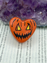 Load image into Gallery viewer, Perfect cute and spooky Halloween item to add to your fridge, locker, cubicle or toolbox. This hand-crafted bright orange heart-shaped magnet showcases a Jack o Lantern inspired design. Measurements: H 1 1/2” x W 1 5/8” x D 1/2”
